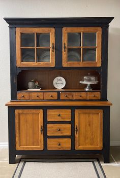 an old fashioned wooden china cabinet with glass doors and drawers on the front, in a kitchen