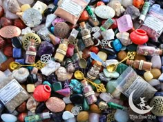 many different types of stones and beads are grouped together on the ground, including one with a charm in it's center