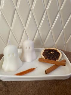 a tray with candles, cinnamon sticks and an orange slice on it in the shape of a ghost