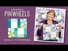 a woman holding up a piece of quilt in front of a purple and green background