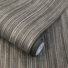 a roll of grey and brown striped fabric on top of a tablecloth with a white button