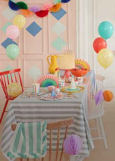 a room filled with lots of colorful balloons and cake on top of a wooden table