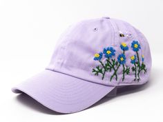 a purple hat with blue flowers embroidered on the front and side, against a white background