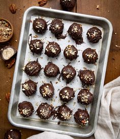 chocolate truffles on a baking sheet with nuts and pecans in the background