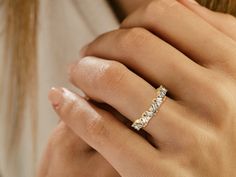 a woman's hand with a diamond ring on her left hand and the other hand holding it