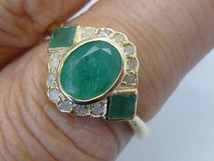 This STUNNING Vintage Inspired ring has been crafted from 9ct Solid Gold. A bezel set HUGE Oval cut NATURAL Emerald brings this ring to life along with two Vibrant Square cut NATURAL Emeralds resting on the shoulders adding additional appeal to this exquisitely feminine ring. Surrounding the face of this GORGEOUS ring are GENUINE Diamonds which have been claw set. This Victorian inspired ring must be seen to be truly appreciated. This ring will add an exotic vintage appeal to any lady who apprec Emerald Ring With Diamonds, Antique Rings Victorian, Womens Rings, Smaragd Ring, Emerald Rings, Vintage Inspired Rings, Victorian Ring, Fancy Rings, Emerald Diamond Ring