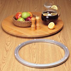 a wooden table topped with a bowl of fruit and a metal ring on top of it