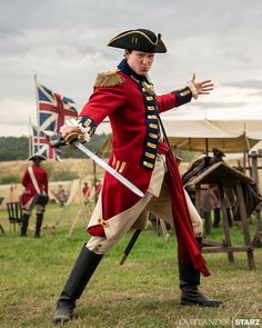 a man dressed as a british soldier with two swords in his hands and one hand out