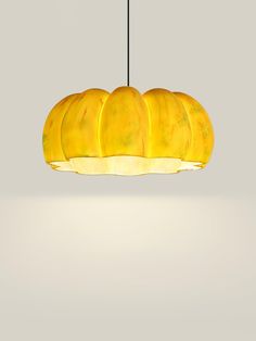 a yellow light hanging from a ceiling with five bananas cut in half on the bottom