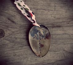 a spoon with a white and green polka dot ribbon hanging from it's side