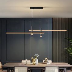 a dining room table and chairs with lights hanging from the ceiling above it, in front of black paneled walls