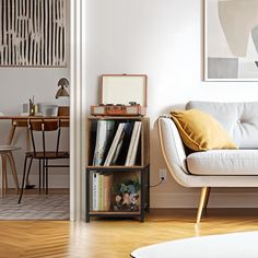 a living room with a white couch and bookshelf next to a dining table