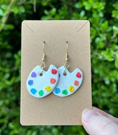 a pair of earrings that have been painted with different colors and shapes, on top of a card