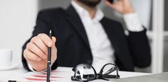 a man sitting at a desk with a pen and eyeglasses in front of him