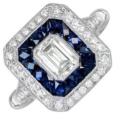 This captivating geometric engagement ring showcases a brilliant GIA-certified emerald cut diamond weighing 0.51 carats, with a G color and VS2 clarity. The center diamond is encircled by a double halo of round brilliant-cut diamonds and French-cut blue sapphires. Crafted in platinum, this ring boasts a sleek, low-profile design. Ring Size: 6.5 US, Resizable Certification: GIA Certificate Color: G Color Clarity: VS2 Metal: Platinum Stone: Diamond, Sapphire Stone Cut: Emerald Cut Style: Art Deco Geometric Engagement Ring, Emerald Cut Diamond Engagement Ring, Emerald Cut Diamond Engagement, Gia Certificate, French Cut, Emerald Cut Diamond, Double Halo, Sapphire Stone, Emerald Cut Diamonds