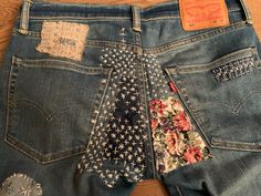 an old pair of jeans with patches and flowers on them, sitting on a wooden floor