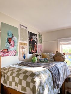 a bedroom with posters on the wall and a teddy bear sitting at the foot of the bed