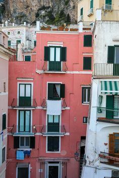 an apartment building with balconies and green shutters on the windows is shown