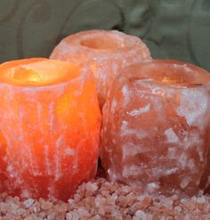 three orange candles sitting on top of gravel