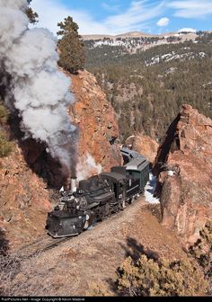 an old fashioned steam train traveling through the mountains