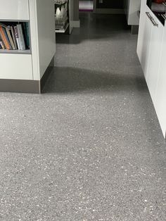 a long narrow hallway with white cabinets and gray flooring