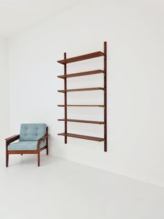 a chair sitting in front of a book shelf next to a wall mounted shelving unit