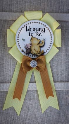 a yellow ribbon with an image of a winnie the pooh on it, and words mommy to be