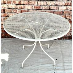 a white table sitting on top of a cement floor next to a brick wall and sidewalk