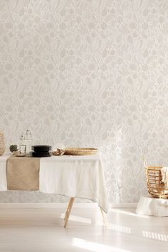 a white table and chairs in front of a wallpapered room with a basket on it