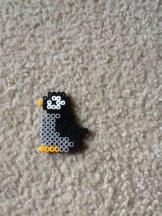 a black and white dog made out of legos on the floor with yellow beads