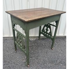 an old wooden table sitting in front of a white wall with a metal frame on it