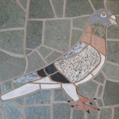 a bird painted on the side of a stone wall next to a brick flooring