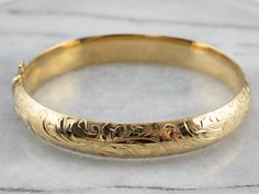 Stunning! The details on this vintage 18 karat gold bangle are simply gorgeous! Intricate botanical designs are engraved in warm yellow gold, covering the entire bracelet. Beautiful on its own or layered with other bracelets this piece is perfect for day or evening wear. Metal: 18K Yellow Gold Width: 11.1 mm Inside Circumference: 7 Inches Marks: "GERMANY 18KO " Stamped Luxury Gold Bracelets With Engraving Option, Luxury Engraved Classic Braided Bracelets, Affordable Engraved Bangle Bracelets, Luxury Handmade Round Gold Bracelet, Luxury Engraved Brass Bracelets, Luxury Brass Bangle Gift, Luxury Brass Engraved Bracelets, Luxury Hand-strung Gold Bracelet Gift, Luxury Engraved Spiritual Bangle