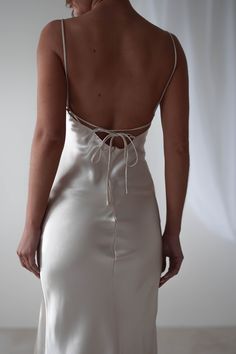 the back of a woman's white dress, with her hands on her hips