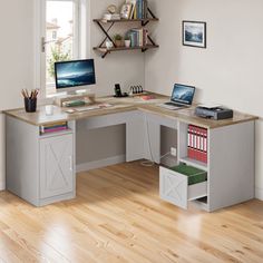 a computer desk with two computers on it and bookshelves in front of the window