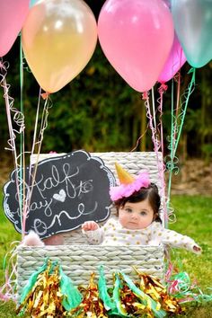 a baby is sitting in a basket with balloons