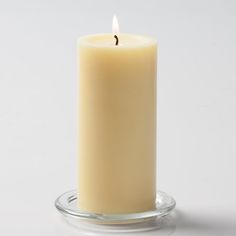 a single white candle sitting on top of a glass holder