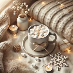 a cup of hot chocolate with marshmallows on a plate and some candles