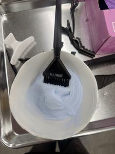 a brush in a white bowl on top of a metal tray