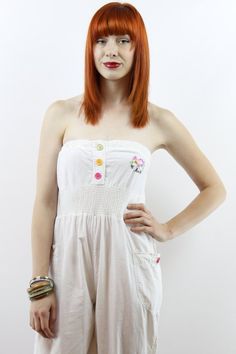 The item: Vintage nineties STRAPLESS WHITE JUMPSUIT. Embroidered emblem at chest. Multi-colored buttons up elastic bust and at ankles. Smocked waist. Side pockets. 100% cotton. To note: There are two stains on this jumpsuit. One at the bust where it looks like it was clipped to a rusty hanger and one that looks like lipstick by the ankles. The price has been reduced accordingly. I have not tried to treat the stains yet. I am going to try and if I am able to get them out, I will edit this listing White Casual Strapless Jumpsuit For Summer, Casual White Strapless Jumpsuit For Summer, White Casual Strapless Jumpsuit For Beach, White Strapless Casual Jumpsuit For Summer, Casual Cotton Strapless Jumpsuit, White Fitted Casual Strapless Jumpsuit, Summer Cotton Strapless Fitted Jumpsuit, Fitted White Strapless Jumpsuit For Spring, White Strapless Stretch Jumpsuit For Spring