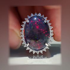 an opal and diamond ring is being held up