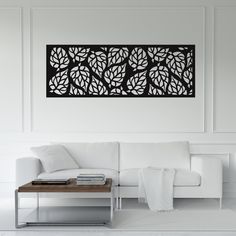 a living room with a white couch and coffee table in front of a wall mounted art piece