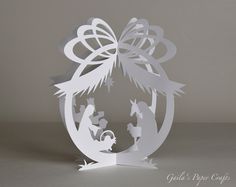 a paper cut nativity scene in the shape of a christmas ornament with an angel