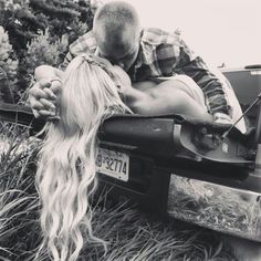 a man and woman kissing in the back of a truck with long blonde hair on it