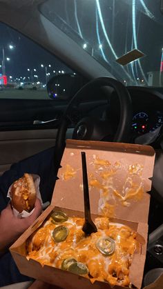 a person holding a pizza in their hand while sitting in the back seat of a car