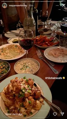 a wooden table topped with plates of food and glasses of wine