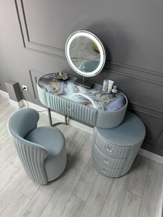 a vanity table with two chairs and a round mirror