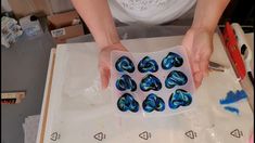 a person holding a plastic container filled with blue marbles on top of a table