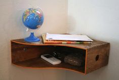 a wooden shelf with a blue globe on top and books in the bottom corner, next to a cell phone