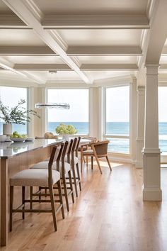 a kitchen with wooden floors and large windows overlooking the ocean is pictured in this image